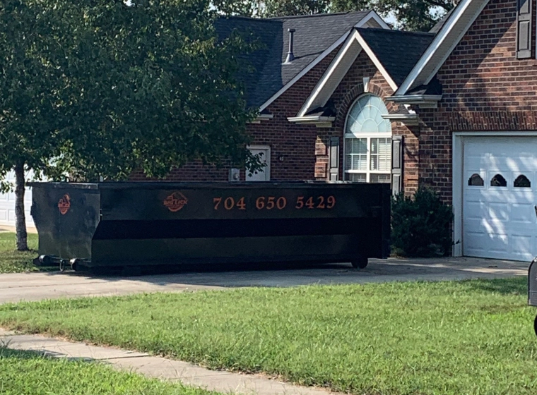 black dumpster parked in house driveeway